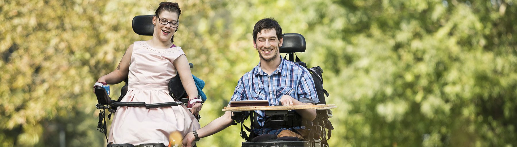Eine Frau und ein Mann im Rollstuhl draußen im Park