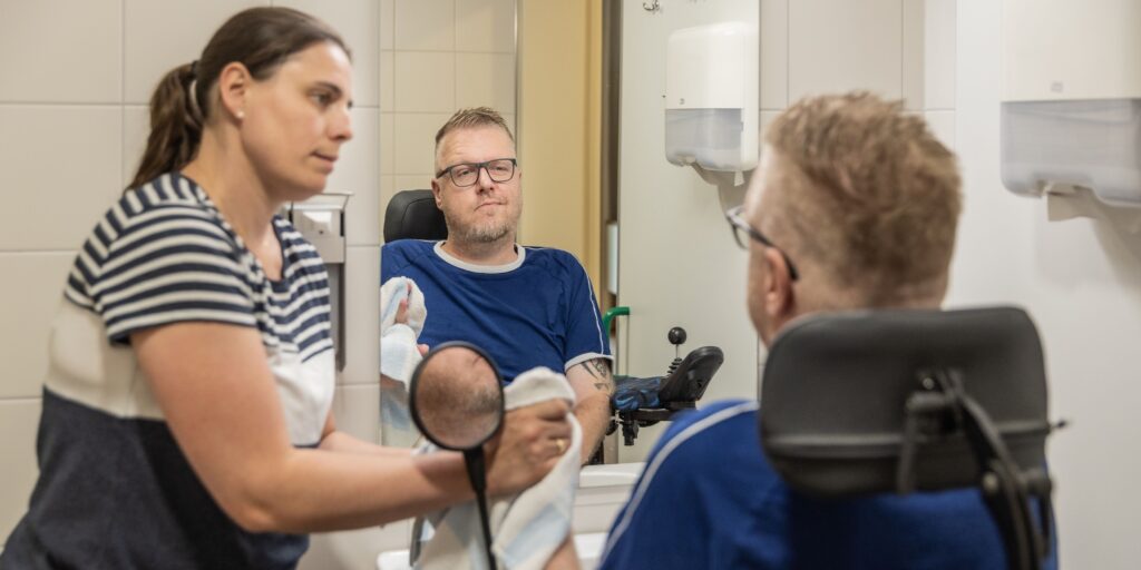 Unterstützung bei der Körperpflege mit skeptischem Blick in den Spiegel